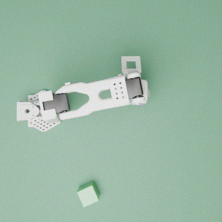 Simulated top view: white arm on a green table with a cube